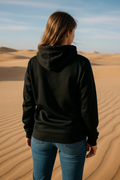 Person wearing a black hoodie and blue jeans standing in a desert landscape