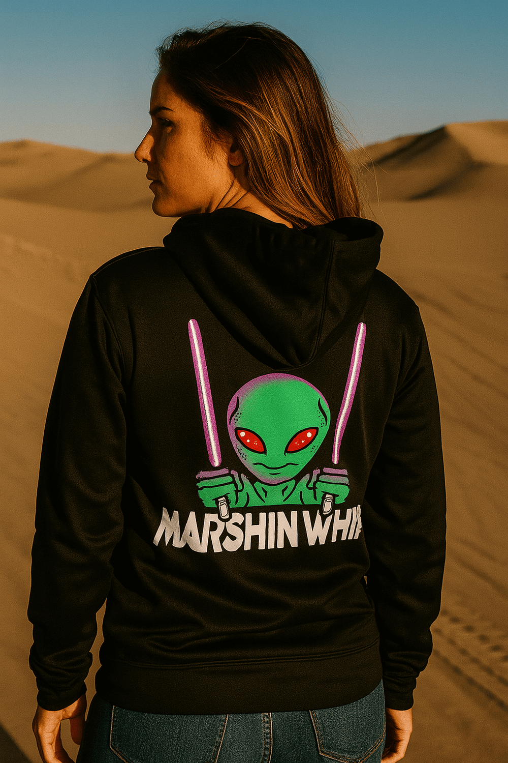 Person wearing a black hoodie with an alien graphic and 'Marshin Whips' text in a desert setting