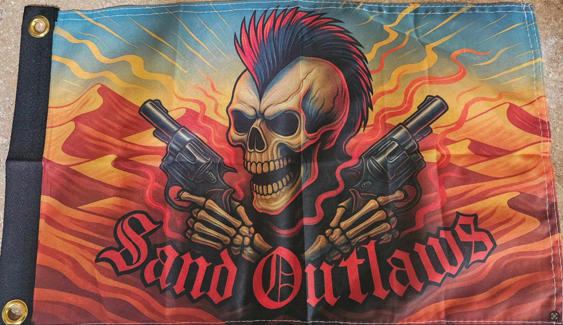 Flag with a skull holding guns and 'Band Outlaws' text against a fiery background