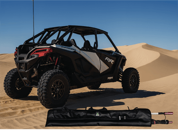 Off-road vehicle on sand dunes with a folded canopy in the foreground