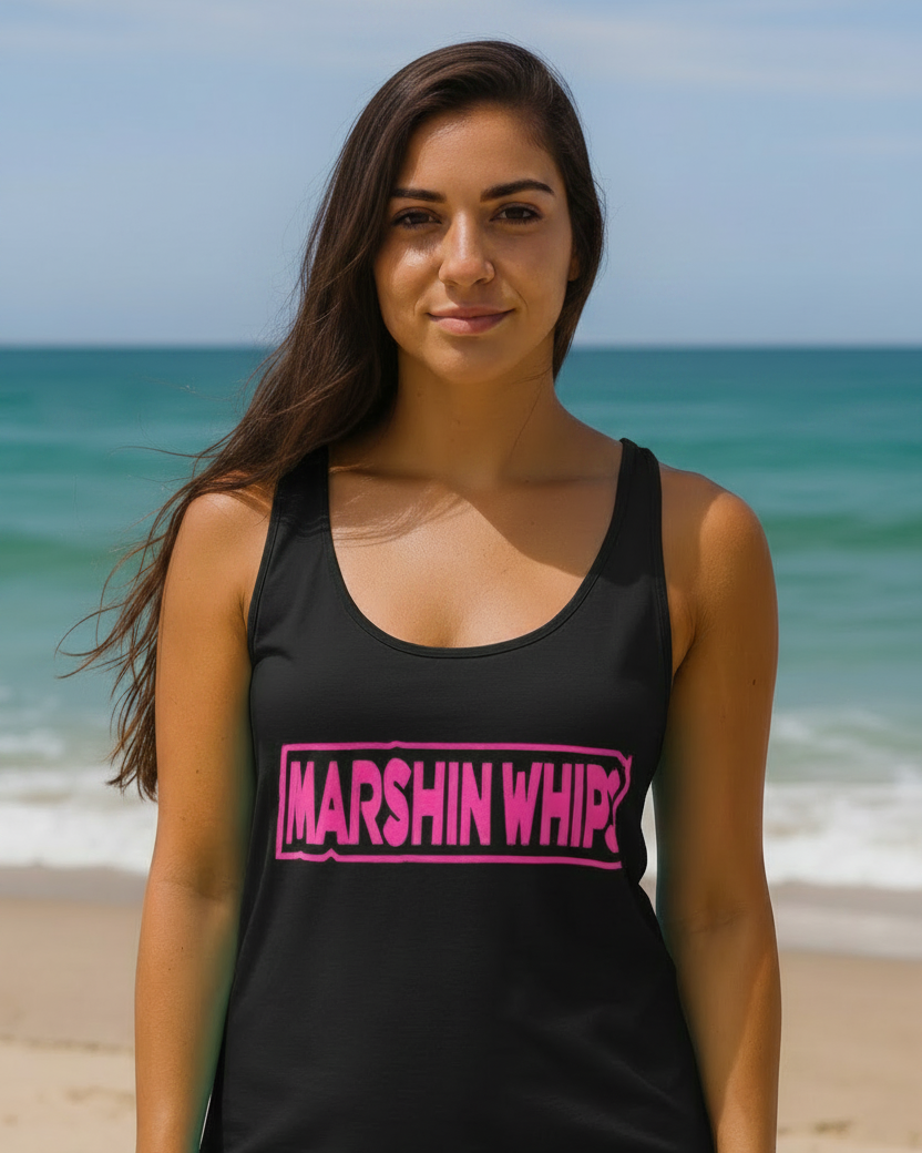 Woman wearing a black tank top and pink beanie with 'Marshin Whips' branding on a beach.