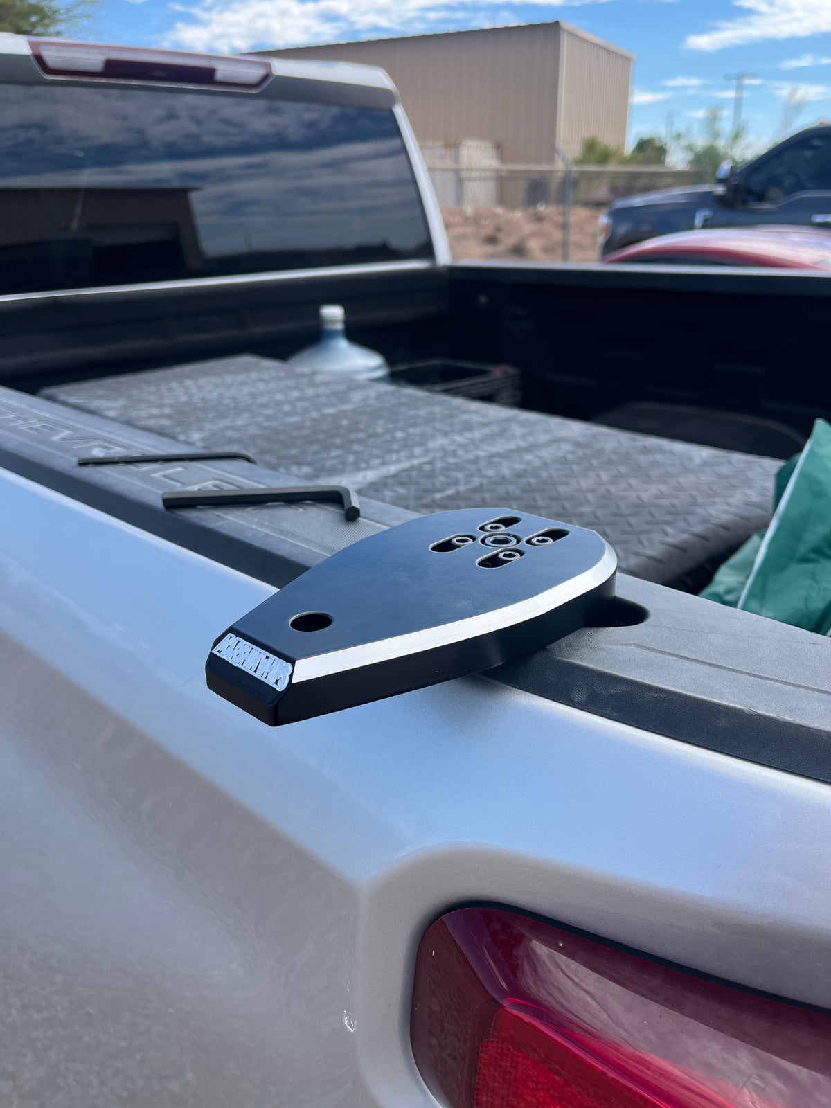 A black and silver Marshin Whips truck bed mount, mounted on the sidereal of a pickup truck.
