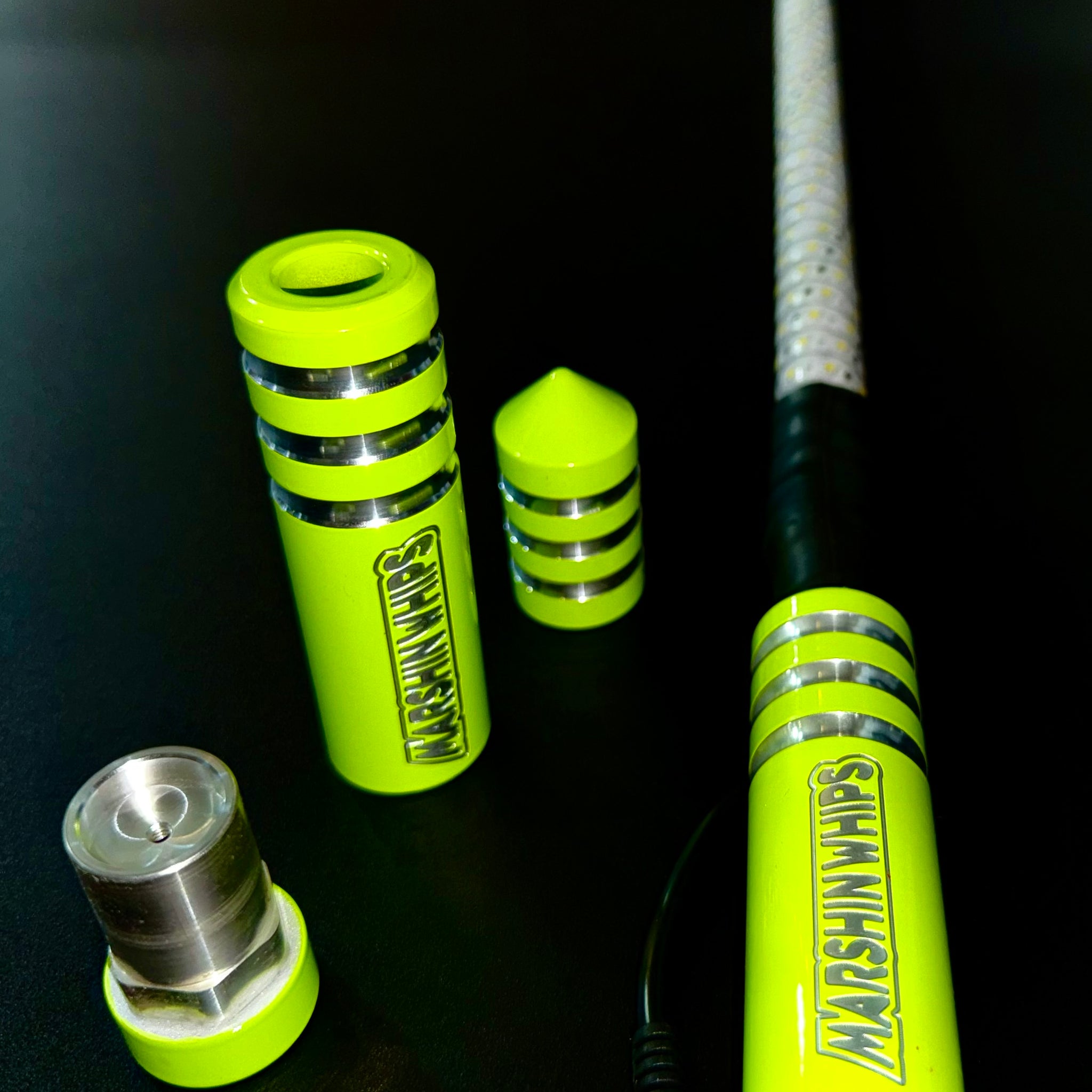 A set of green Game Changer Whips with metallic accents, displayed on a dark background, highlighting their design and construction.
