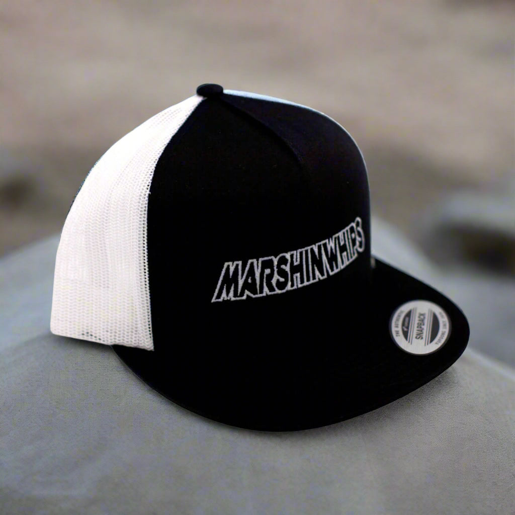 Black and white cap with 'MARSHIN WHIPS' logo on a blurred background